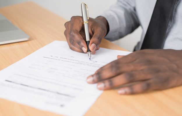 person-holding-gray-twist-pen-and-white-printer-paper-on-955389